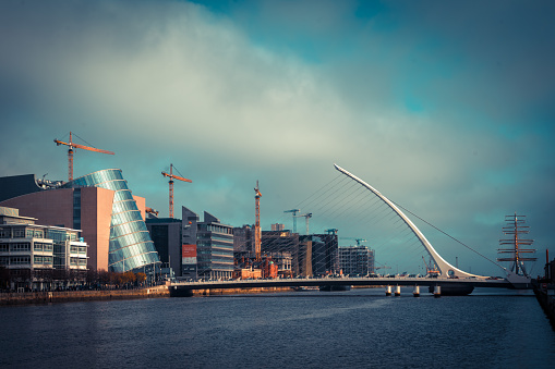 Wide view of Samuel Beckett bridge in Dublin city centre, Ireland. With Convention Centre in background shot on winter day with hazy low winter sun and cloudy sky