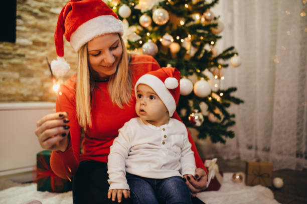 Beautiful young mother with her son celebrating New Year or Christmas at home