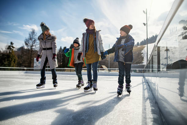 Family enjoying ice-skating together Mother and three kids spending time on ice-skating rink. 
Nikon D850 ice skating stock pictures, royalty-free photos & images