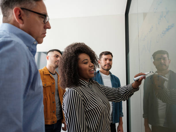 istock Latin business young woman writing on whiteboard at work 1185430857
