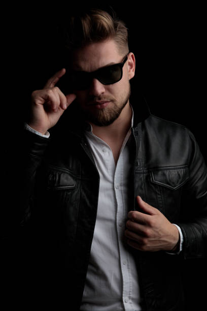 istock casual man standing and fixing his sunglasses and jacket 1185431034