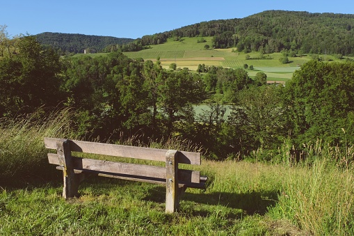 Wooden long chair on hill with beautiful view in Switzerland.
