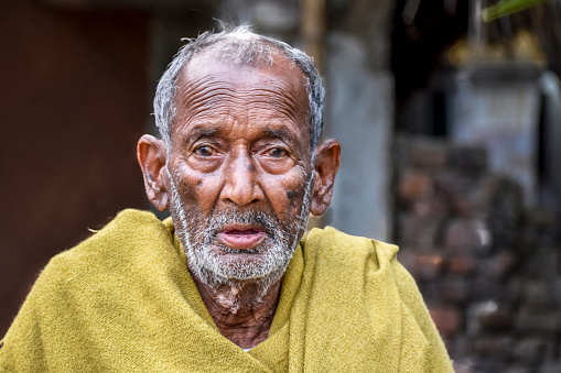 A poor indigenous old man of India looks at the camera with astonished eyes
