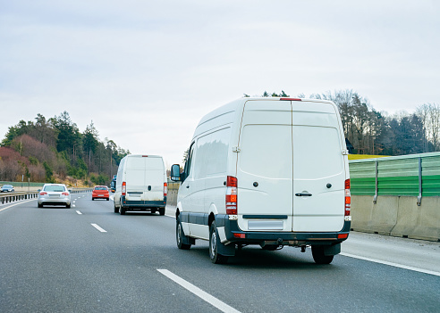 White Minivans on road. Mini van auto vehicle on driveway. European van transport logistics transportation. Auto with driver on highway.