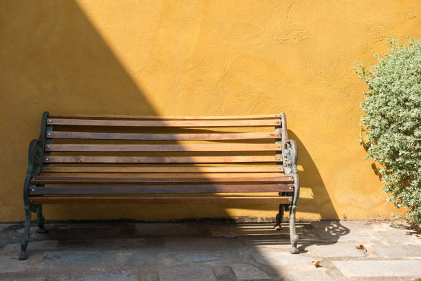 istock bench chair near yellow wall 1185434523