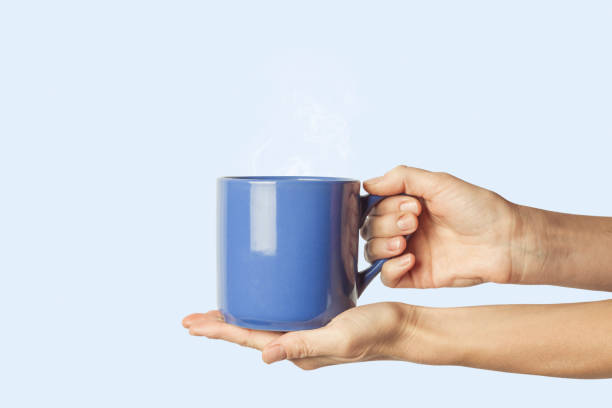 istock Female hand holding a blue cup on a blue background. Side view 1185435344