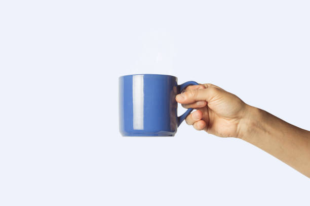istock Female hand holding a blue cup on a blue background. Side view 1185435487