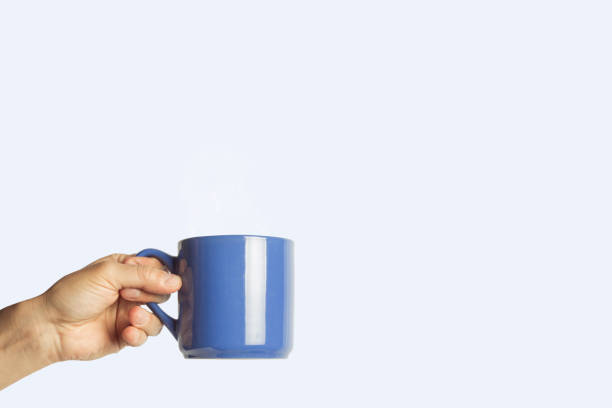 istock Female hand holding a blue cup on a blue background. Side view 1185435800