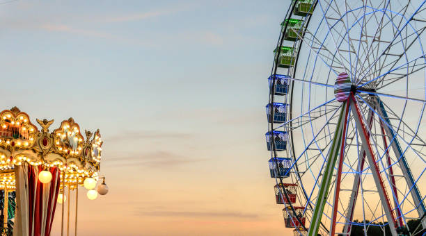 ruota panoramica in un parco fieristico vicino a una giostra - ferris wheel immagine foto e immagini stock