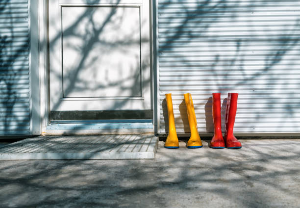 yellow and blue rubber boots near white door (on the doorstep of the house)