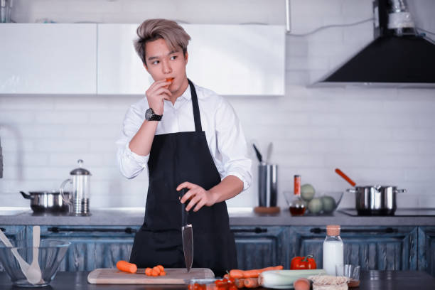 Asian cook in the kitchen prepares food in a cook suit