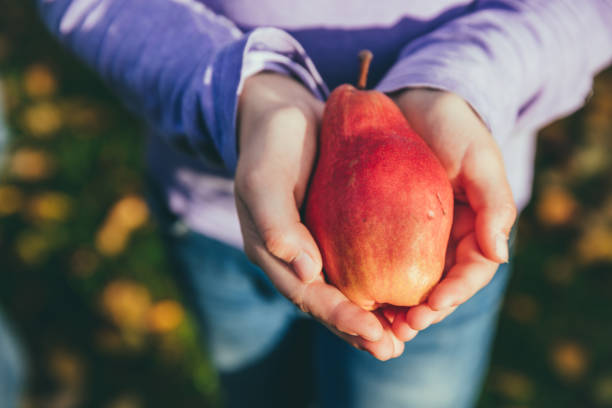 young woman holding pear in her hand