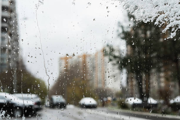 istock Blurred town behind Melted snow texture on the car window. Winter background 1185442182