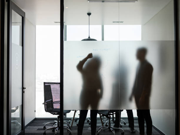 istock Business people standing and writing on transparent board 1185442459