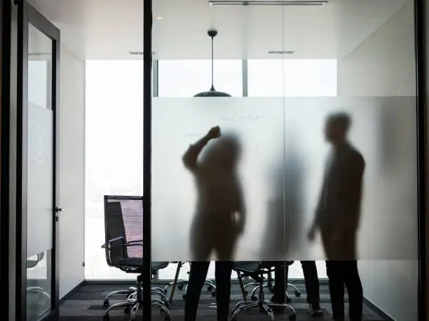 Photo of Business people standing and writing on transparent board