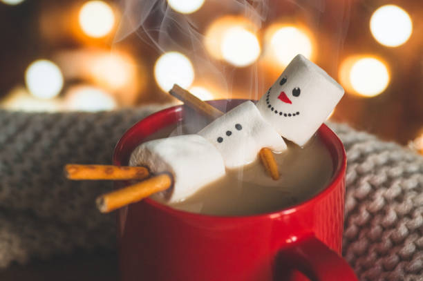 Red mug with hot chocolate with melted marshmallow snowman Red mug with hot chocolate with melted marshmallow snowman on bokeh background snowman stock pictures, royalty-free photos & images