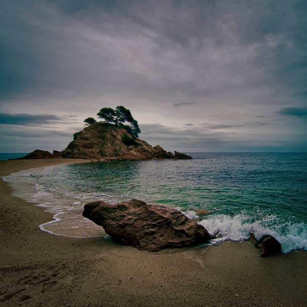 Cove on a grey day with a characteristic rock in the foreground near the water.