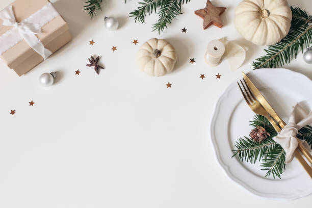Traditional Christmas table place setting. Golden cutlery, porcelain plate, fir tree branches, gift box, pine cones and white pumkins. Christmas baubles decoration. Holidays background. Flat lay, top. Traditional Christmas table place setting. Golden cutlery, porcelain plate, fir tree branches, gift box, pine cones and white pumkins. Christmas baubles decoration, holidays background. Flat lay, top. restaurant table layout stock pictures, royalty-free photos & images