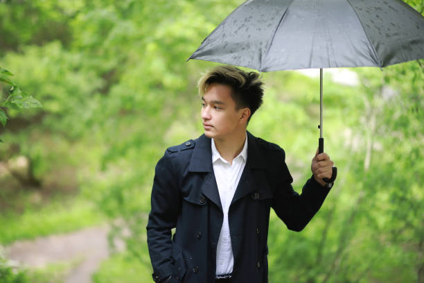 istock Spring rainy weather and a young man with an umbrella 1185454838