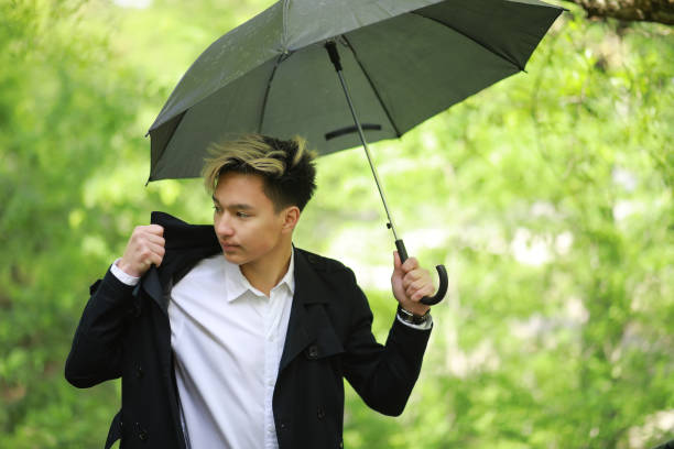 istock Spring rainy weather and a young man with an umbrella 1185454870