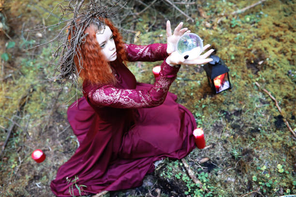 istock The red-haired witch holds a ritual with a crystal ball 1185456307