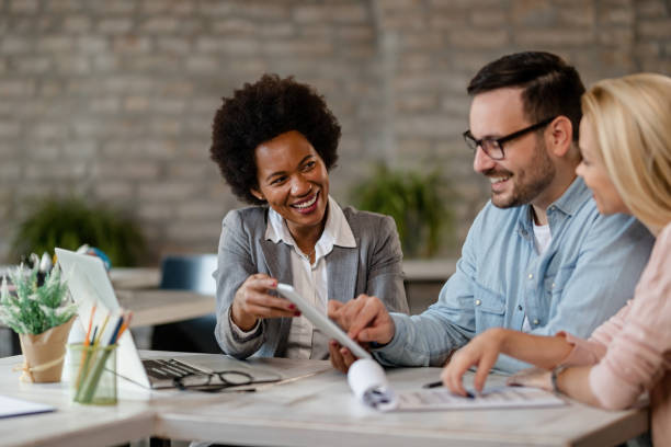 istock Happy black insurance agent and a couple using touchpad in the office. 1185459830