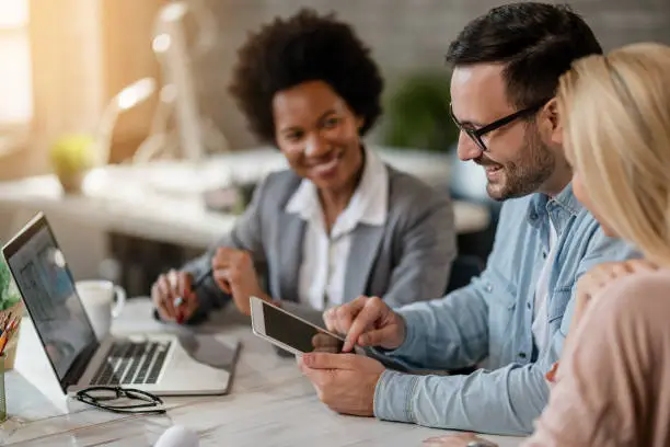 Photo of Happy couple using touchpad on a meeting with real estate agent.