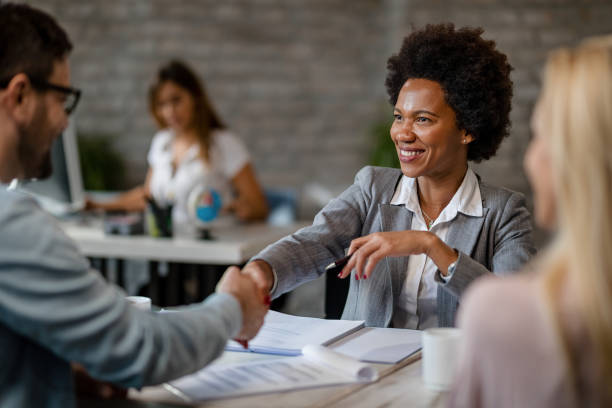 istock Black happy financial advisor shaking hands with clients in the office. 1185461739