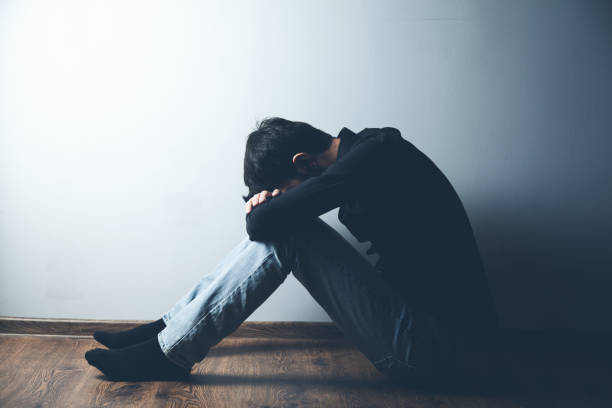 istock sad man sitting on ground on dark background 1185463949