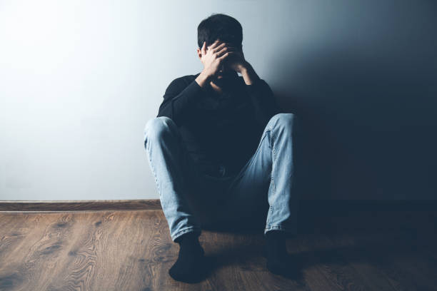 istock sad man sitting on ground on dark background 1185463950