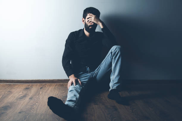 istock sad man sitting on ground on dark background 1185463968