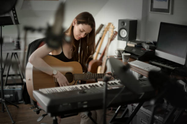 Guitar studio woman Stock photo of a beautiful young woman playing an acoustic guitar whilst seated in a music recording studio. making music stock pictures, royalty-free photos & images