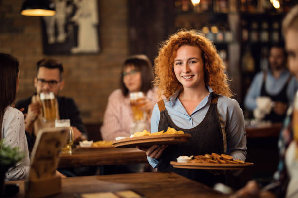 istock Young happy waitress serving her guest in a pub. 1185466516