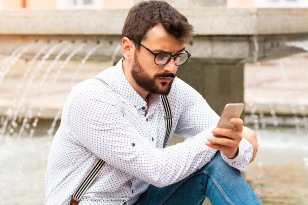 istock Man sitting on fountaing and using smart phone. 1185467071