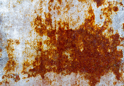 Brown and yellow rust on white enamel, corroded metal background. Rusty painted metal wall.