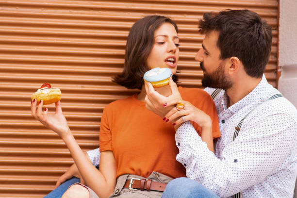 istock Couple eating donuts on street. 1185467284