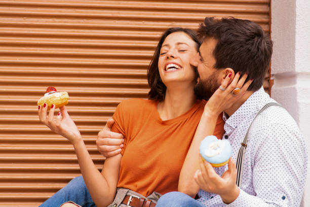 istock Couple eating donuts on street. 1185467286