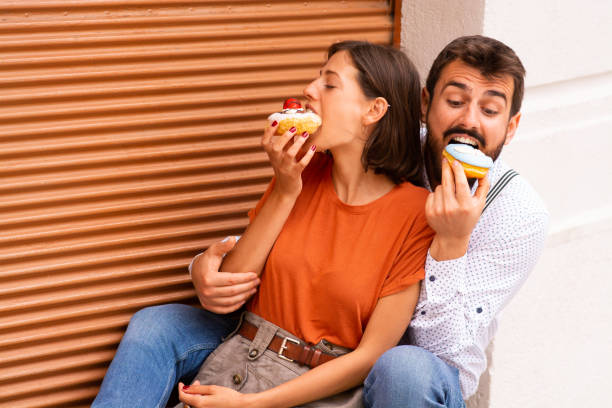 istock Couple eating donuts on street. 1185467442