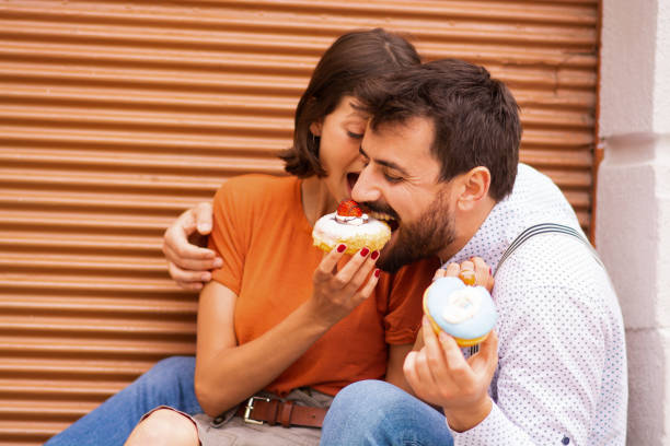 istock Couple eating donuts on street. 1185467454