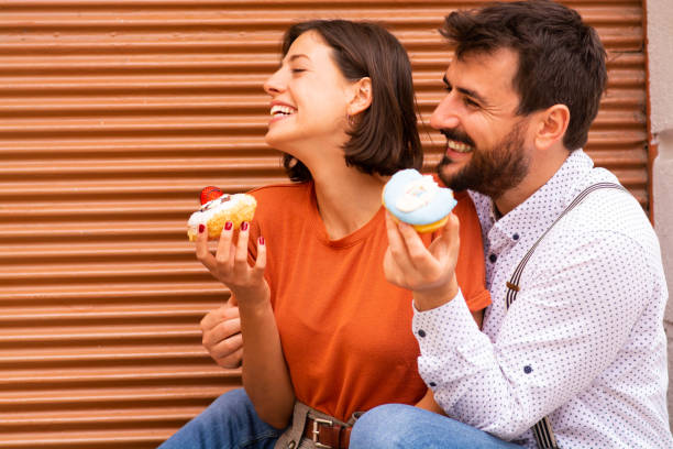 istock Couple eating donuts on street. 1185467637