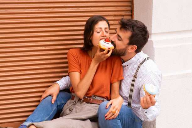 istock Couple eating donuts on street. 1185467666
