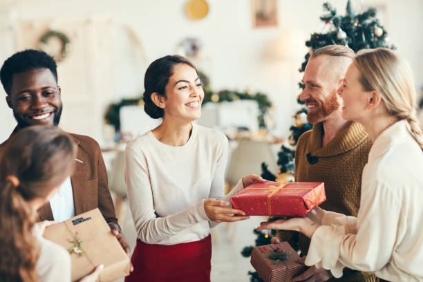 Presenting Christmas Gifts Group of elegant young people exchanging gifts and smiling cheerfully during Christmas party, copy space guest photos stock pictures, royalty-free photos & images