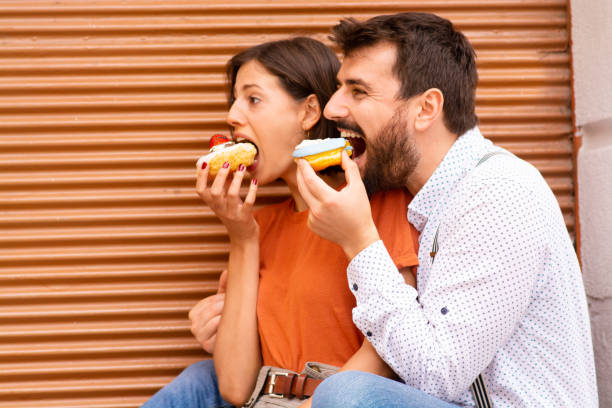 istock Couple eating donuts on street. 1185468274