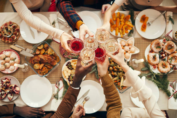 Celebration Toast over Festive Dinner Table Top view background of people raising glasses over festive dinner table while celebrating Christmas with friends and family, copy space people banque stock pictures, royalty-free photos & images