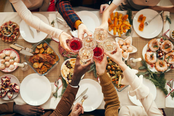 Celebration Toast over Festive Dinner Table Top view background of people raising glasses over festive dinner table while celebrating Christmas with friends and family, copy space top honor stock pictures, royalty-free photos & images