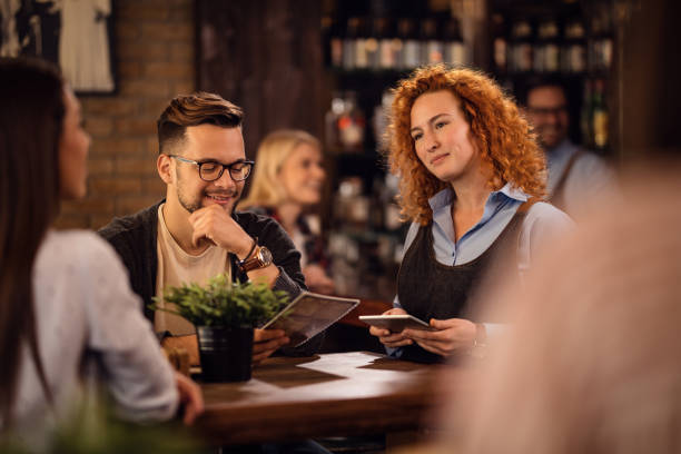 istock Happy waitress with touchpad taking order form a guests in a bar. 1185468426