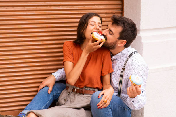 istock Couple eating donuts on street. 1185468440
