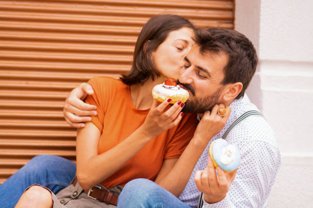 istock Couple eating donuts on street. 1185468442