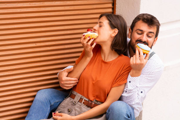 istock Couple eating donuts on street. 1185468527