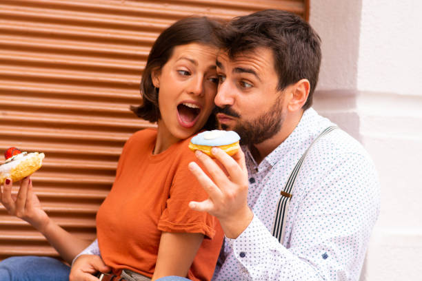 istock Couple eating donuts on street. 1185468615
